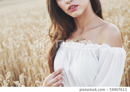Young sensitive girl in white dress posing in a field of golden wheat 59907613
