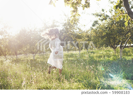 Beautiful young woman wearing elegant white dress and enjoying beautiful sunny afternoon in a summer 59908183