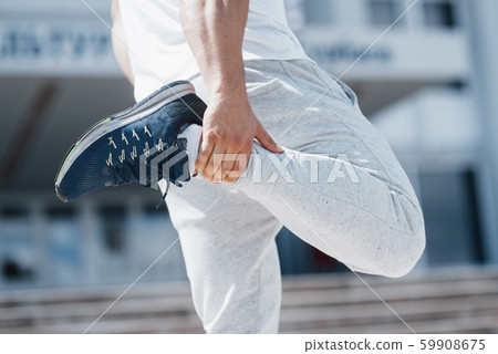 A handsome fitness man in a sportswear, doing stretching while preparing for serious exercise in the A handsome fitness man in a sportswear, doing stretching while preparing for serious exercise in the 59908675