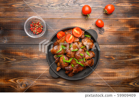 Homemade chicken liver fried with soy sauce, tomatoes, onions and spices on wood background. Top 59909409