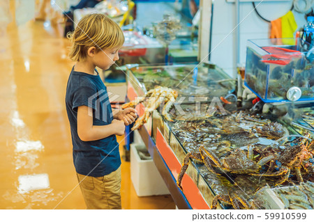 Boy in the Korean market. Raw seafood at Noryangjin Fisheries Wholesale Market in Seoul, South Korea Boy in the Korean market. Raw seafood at Noryangjin Fisheries Wholesale Market in Seoul, South Korea 59910599