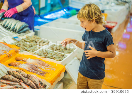 Boy in the Korean market. Raw seafood at Noryangjin Fisheries Wholesale Market in Seoul, South Korea Boy in the Korean market. Raw seafood at Noryangjin Fisheries Wholesale Market in Seoul, South Korea 59910655