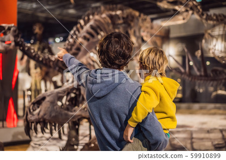 Dad and boy watching dinosaur skeleton in museum Dad and boy watching dinosaur skeleton in museum 59910899