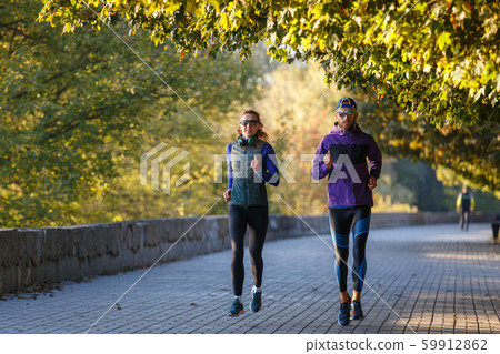 Young couple running in autumn park in the morning 59912862