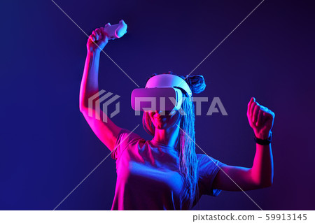 Woman is using virtual reality headset. Neon light studio portrait. 59913145
