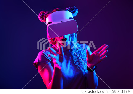 Woman is using virtual reality headset. Neon light studio portrait. 59913159