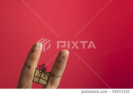 Funny fingers couple holding present gift box against red background with copy space for ad text Funny fingers couple holding present gift box against red background with copy space for ad text 59915192