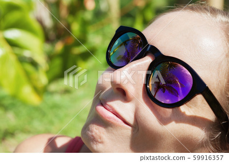 Woman wearing sunglasses with palms, sky 59916357