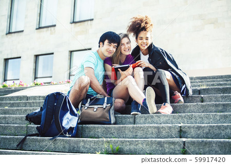 cute group of teenages at the building of university with books huggings, diversity nations real 59917420