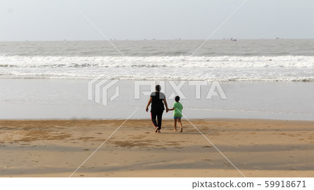 Rear View of Mother and son walking on a tropical beach in evening during sunset. Rear View of Mother and son walking on a tropical beach in evening during sunset. 59918671