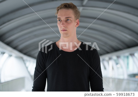 Young handsome man with curly hair thinking outdoors Young handsome man with curly hair thinking outdoors 59918673