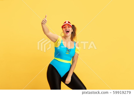 Young caucasian plus size female model's training on yellow background Young caucasian plus size female model's training on yellow background 59919279