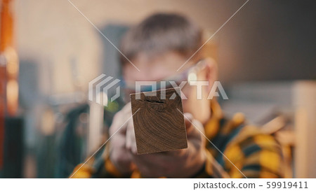 Carpentry indoors - a man woodworker inspect cuted detail for the imperfections in perspective 59919411