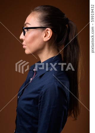 Young beautiful businesswoman wearing eyeglasses against brown b 59919432
