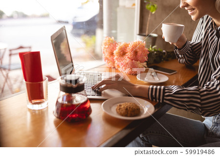 Cheerful woman working remotely from the cafe 59919486