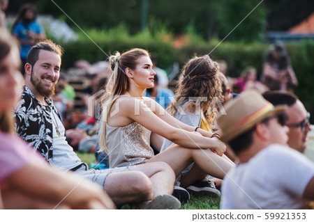 Group of young friends sitting on ground at summer festival. 59921353