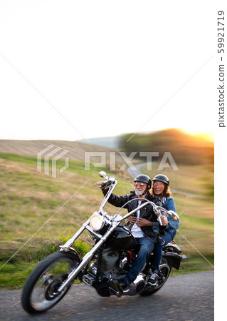 A cheerful senior couple travellers with motorbike in countryside. 59921719