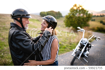 A cheerful senior couple travellers in love with motorbike in countryside. 59921735