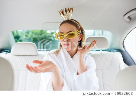 Young woman with party accessories sitting in car, having fun. Young woman with party accessories sitting in car, having fun. 59922608