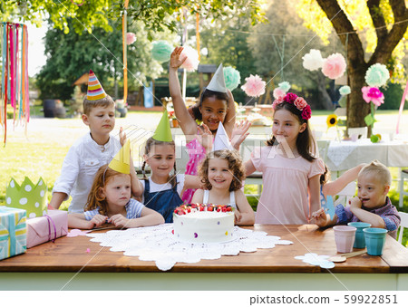 Down syndrome child with friends on birthday party outdoors in garden. Down syndrome child with friends on birthday party outdoors in garden. 59922851