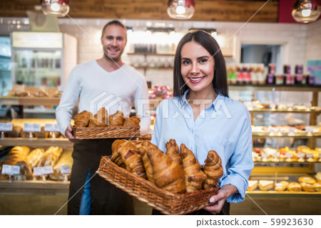 Woman owning bakery with husband holding just baked croissants Woman owning bakery with husband holding just baked croissants 59923630