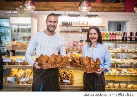 Couple holding boxes with croissants standing in their bakery Couple holding boxes with croissants standing in their bakery 59923632