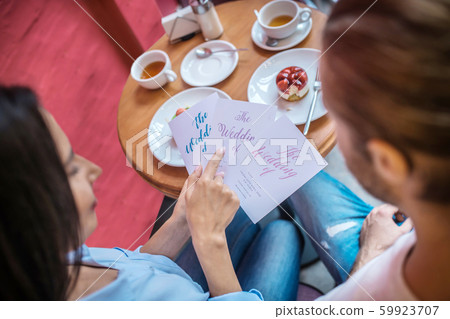 Top view of boyfriend and girlfriend looking at wedding invitations 59923707