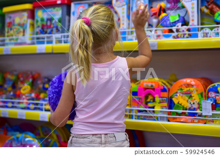 Girl looks in the window of children toy shop Girl looks in the window of children toy shop 59924546