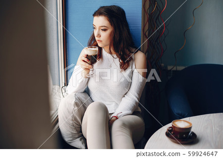 Girl in a white sweater sitting alone in cafe Girl in a white sweater sitting alone in cafe 59924647