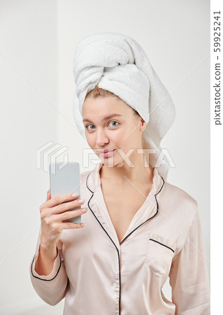 Pretty young female in silk pajamas going to make selfie while looking at you Pretty young female in silk pajamas going to make selfie while looking at you 59925241