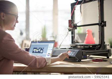 Creative female designer pushing button on control panel of 3d printer Creative female designer pushing button on control panel of 3d printer 59925341