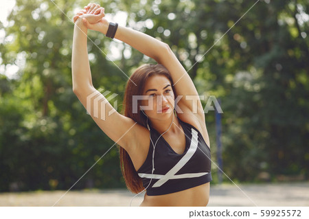 Sports girl training with headphones in a summer park Sports girl training with headphones in a summer park 59925572