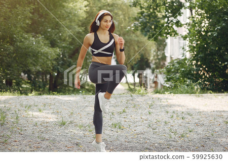 Sports girl training with headphones in a summer park 59925630