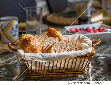 Bread and croissants on a table with berries on a background in the yard. 59927596
