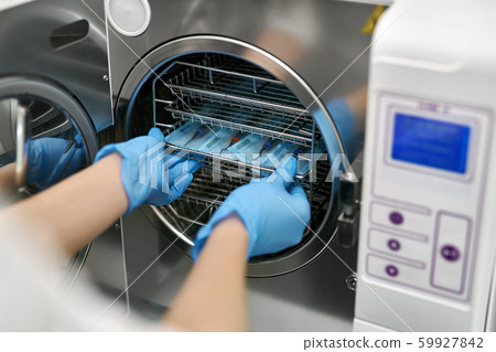 Dentist is loading dental probes into sterilize machine 59927842