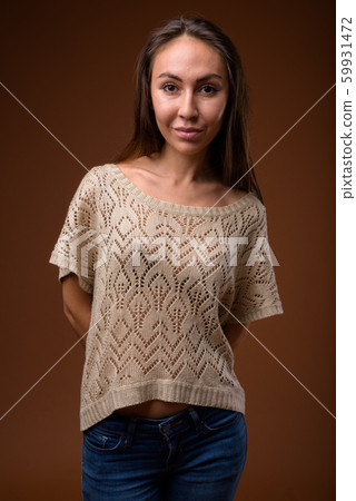 Studio shot of young beautiful woman against brown background 59931472