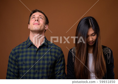 Studio shot of young multi-ethnic couple together against brown 59931850