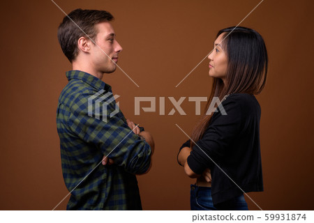 Studio shot of young multi-ethnic couple together against brown Studio shot of young multi-ethnic couple together against brown 59931874
