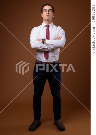 Young handsome businessman wearing eyeglasses against brown back Young handsome businessman wearing eyeglasses against brown back 59932298