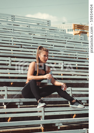 Tired woman in headphones resting and drinking 59934404