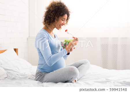 African-american expectant girl enjoying healthy vegetable salad African-american expectant girl enjoying healthy vegetable salad 59941548