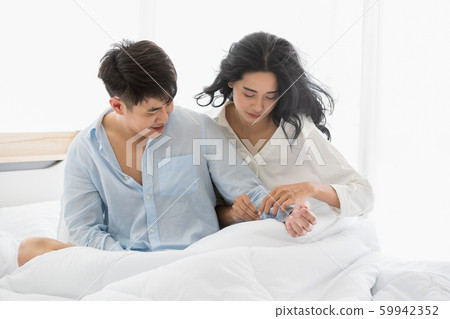 Couple sits on bed, they hug each other by love.. 59942352