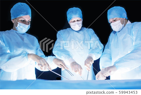 Three surgeons, a man and a woman, perform surgery in the operating room to remove and transplant human organs, resect the stomach and remove the gallbladder, appendicitis 59943453