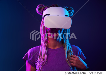 Woman is using virtual reality headset. Neon light studio portrait. 59943503