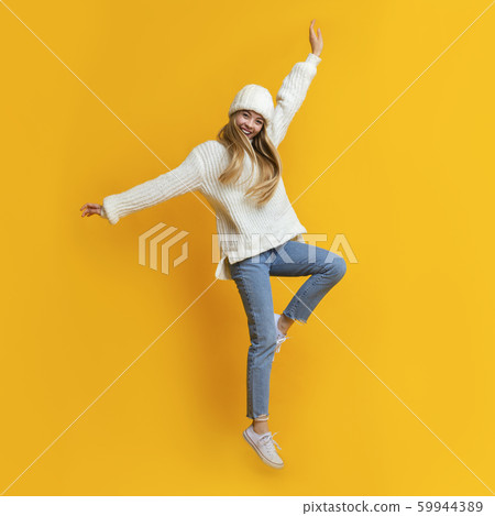 Playful winter girl having fun over yellow studio background Playful winter girl having fun over yellow studio background 59944389