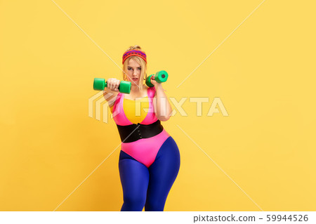 Young caucasian plus size female model's training on yellow background Young caucasian plus size female model's training on yellow background 59944526