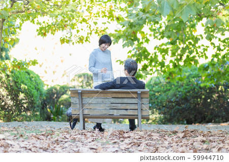 Back view senior couple snuggling on bench autumn happy family couple travel Back view senior couple snuggling on bench autumn happy family couple travel 59944710
