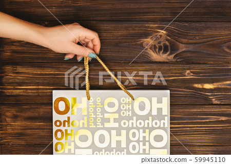 Cropped shot of female hand with Christmas paper bag for presents. Cropped shot of female hand with Christmas paper bag for presents. 59945110