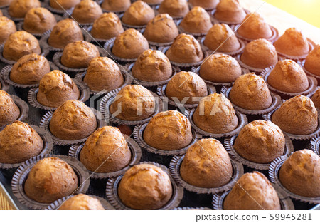 Lots of delicious fresh chocolate muffins muffins on a tray, background, copy space, dessert, manufacturing Lots of delicious fresh chocolate muffins muffins on a tray, background, copy space, dessert, manufacturing 59945281