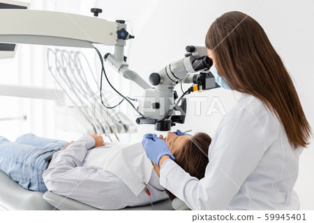 Professional female dentist using modern technologies in treatment 59945401